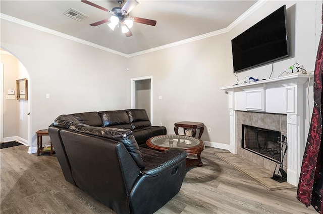 living room featuring hardwood / wood-style floors, ceiling fan, ornamental molding, and a fireplace