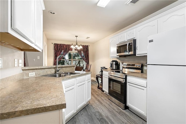 kitchen with hardwood / wood-style floors, sink, appliances with stainless steel finishes, a notable chandelier, and white cabinetry