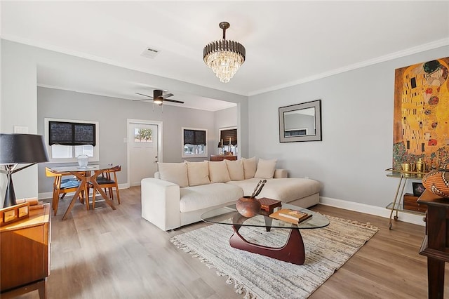 living room with ceiling fan with notable chandelier, light hardwood / wood-style floors, and ornamental molding