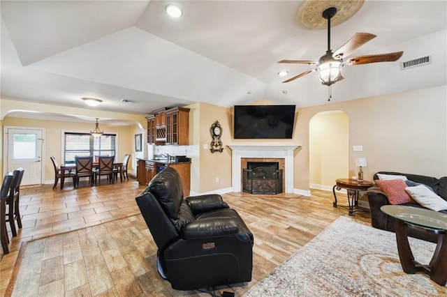 living room with ceiling fan, wood-type flooring, and lofted ceiling