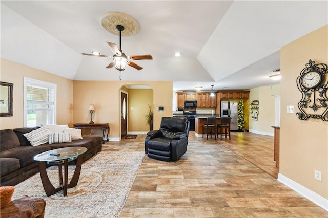 living room with ceiling fan, light hardwood / wood-style flooring, and lofted ceiling