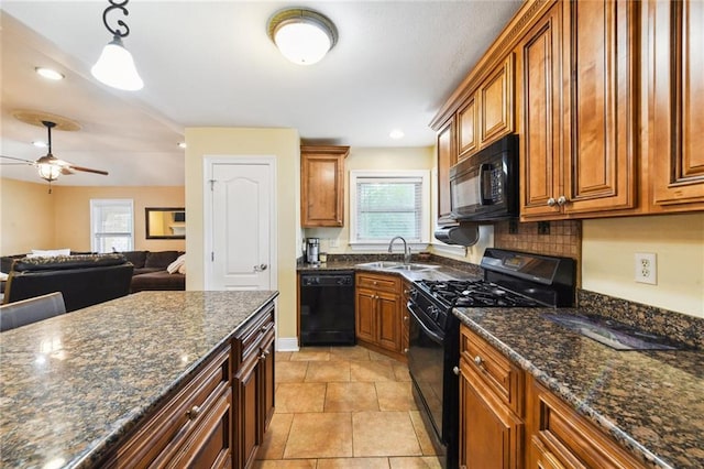 kitchen featuring sink, tasteful backsplash, dark stone counters, decorative light fixtures, and black appliances