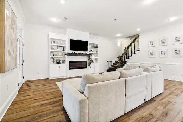 living room featuring hardwood / wood-style floors, built in shelves, and crown molding