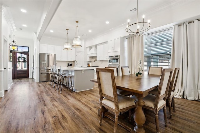 dining space featuring a chandelier, wood-type flooring, crown molding, and sink