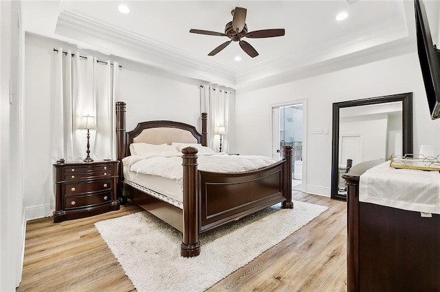 bedroom with a tray ceiling, ensuite bathroom, ceiling fan, and light hardwood / wood-style floors