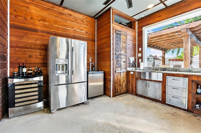 kitchen with wood walls, stainless steel fridge with ice dispenser, and sink