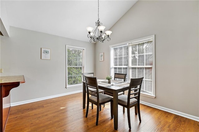 dining space featuring hardwood / wood-style flooring, lofted ceiling, and a notable chandelier