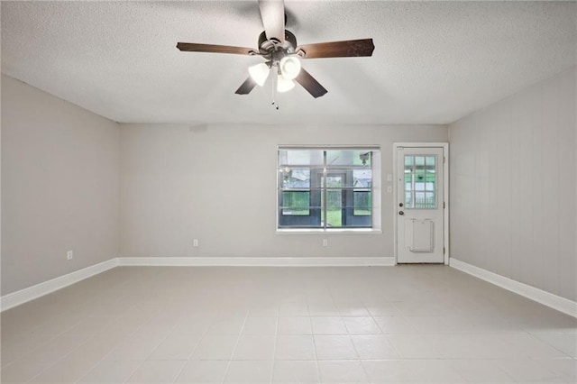 unfurnished room featuring wooden walls, ceiling fan, and a textured ceiling