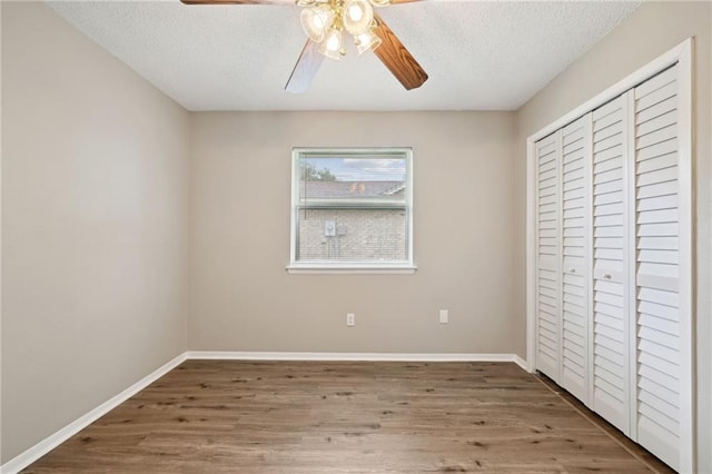 unfurnished bedroom with a textured ceiling, hardwood / wood-style flooring, a closet, and ceiling fan