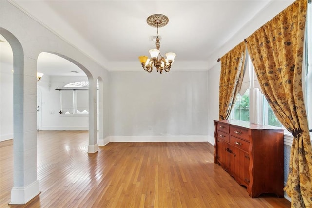 unfurnished dining area featuring a notable chandelier and light hardwood / wood-style floors