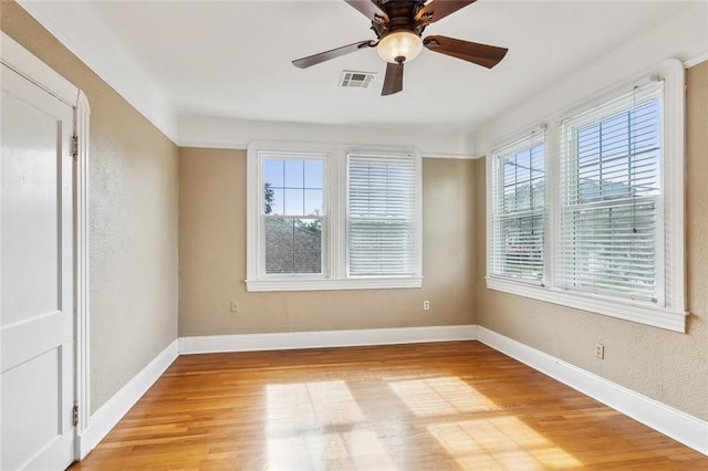 empty room featuring ceiling fan, a healthy amount of sunlight, and wood-type flooring