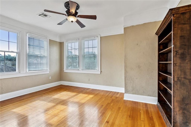 empty room with ceiling fan, light hardwood / wood-style flooring, and a healthy amount of sunlight