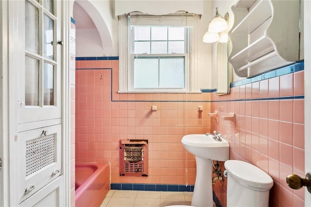 bathroom with tile patterned floors, toilet, a bathing tub, and tile walls