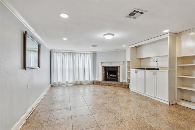 unfurnished living room featuring built in shelves, light tile patterned flooring, ornamental molding, and a brick fireplace