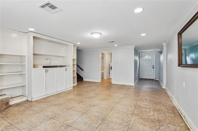 unfurnished living room with built in shelves, light tile patterned flooring, washer / dryer, and ornamental molding