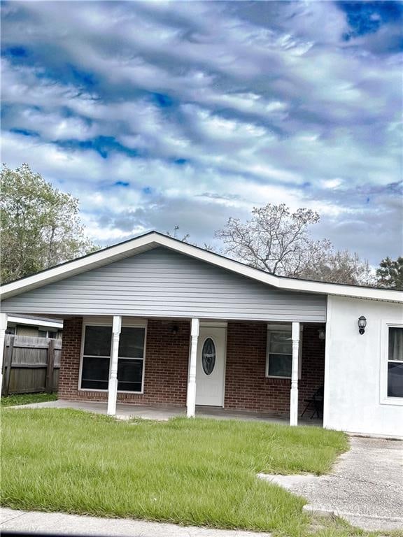 ranch-style house featuring covered porch and a front lawn