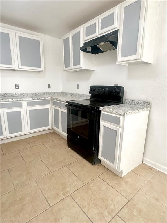 kitchen with black electric range oven, light stone counters, white cabinetry, and light tile patterned floors