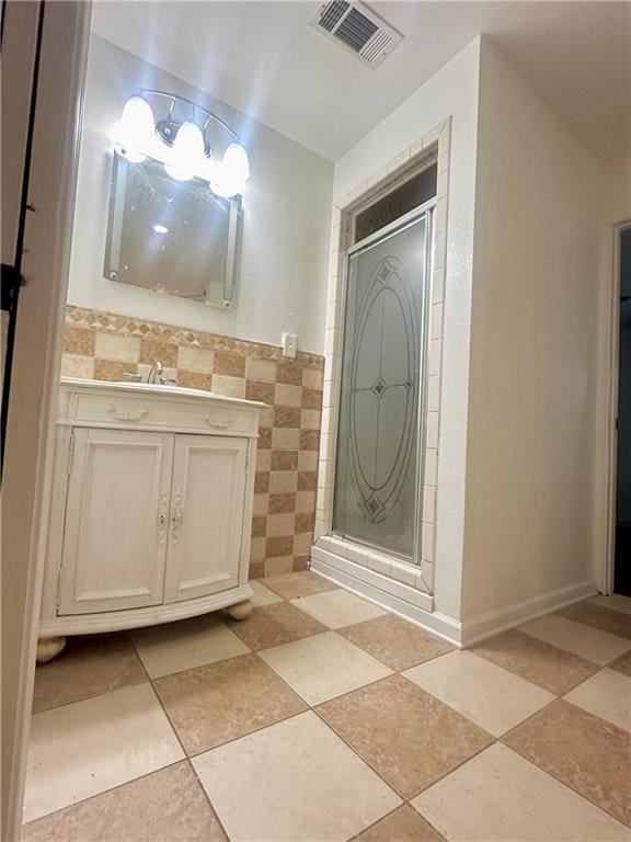 bathroom with an enclosed shower, vanity, tile patterned floors, and tile walls