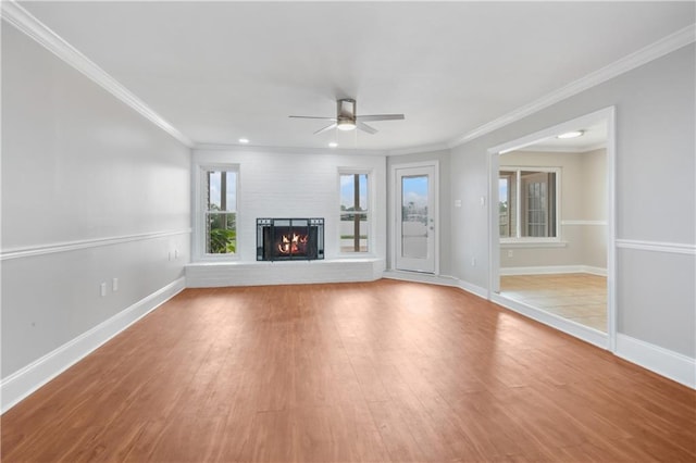 unfurnished living room featuring ceiling fan, crown molding, wood-type flooring, and a fireplace