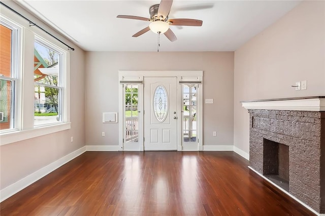 entrance foyer with a stone fireplace, ceiling fan, and dark hardwood / wood-style floors