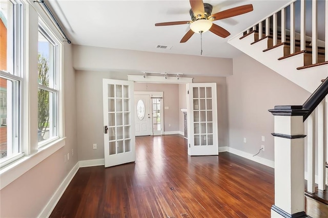 spare room featuring plenty of natural light, ceiling fan, dark hardwood / wood-style flooring, and french doors