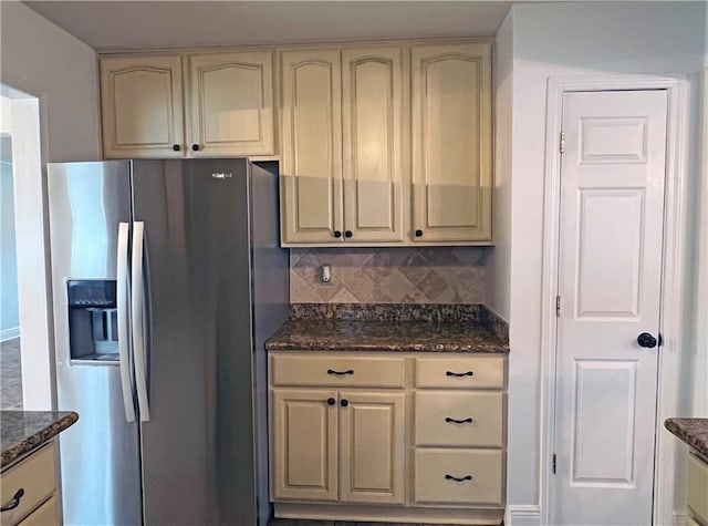 kitchen featuring stainless steel fridge with ice dispenser, tasteful backsplash, and dark stone countertops