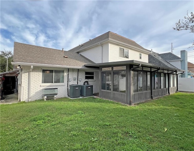 rear view of property featuring a sunroom, a lawn, and central AC