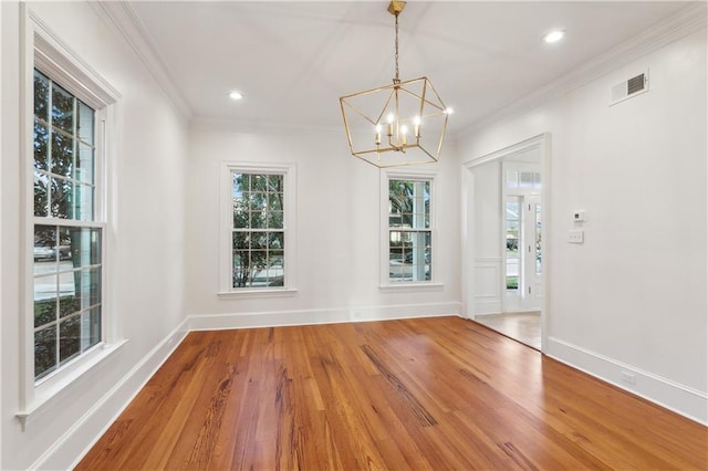 unfurnished dining area with hardwood / wood-style floors, an inviting chandelier, and crown molding