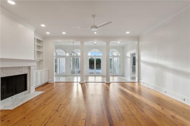 unfurnished living room featuring built in shelves, light hardwood / wood-style flooring, ceiling fan, and crown molding