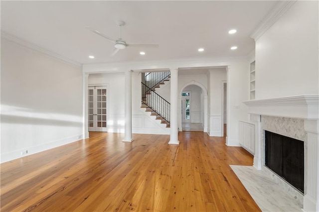 unfurnished living room with built in shelves, light hardwood / wood-style flooring, ceiling fan, and ornamental molding