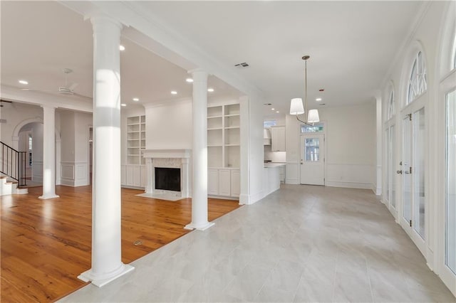 unfurnished living room featuring built in shelves, light hardwood / wood-style flooring, french doors, and ornamental molding