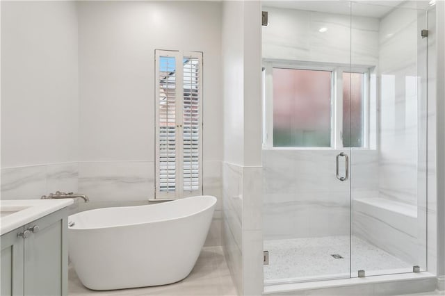 bathroom featuring separate shower and tub, vanity, and tile walls