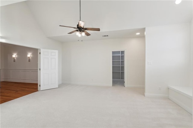 carpeted empty room featuring ceiling fan and high vaulted ceiling