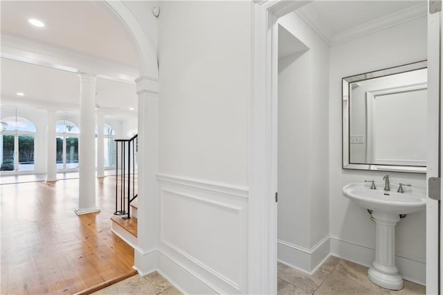 bathroom featuring ornate columns, ornamental molding, and hardwood / wood-style flooring