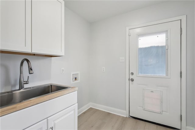 laundry area featuring cabinets, sink, washer hookup, and light wood-type flooring