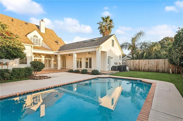 back of house featuring ceiling fan, cooling unit, a fenced in pool, and a patio