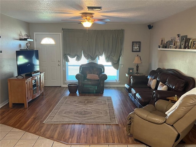 living room featuring hardwood / wood-style flooring, ceiling fan, and a textured ceiling