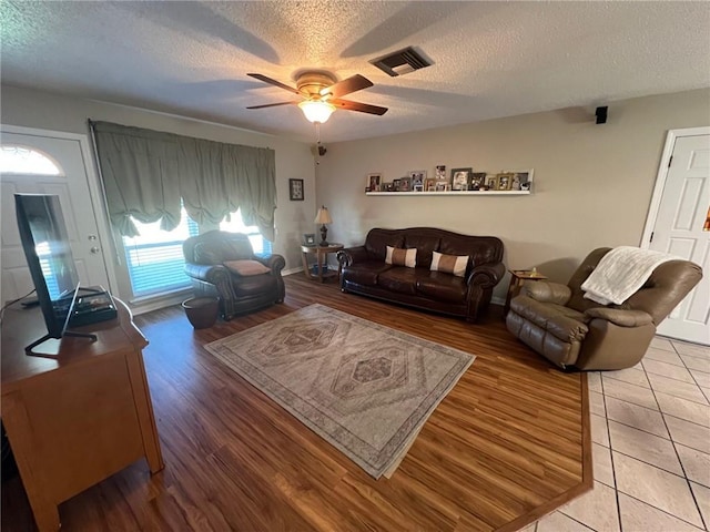 living room featuring ceiling fan, wood-type flooring, and a textured ceiling