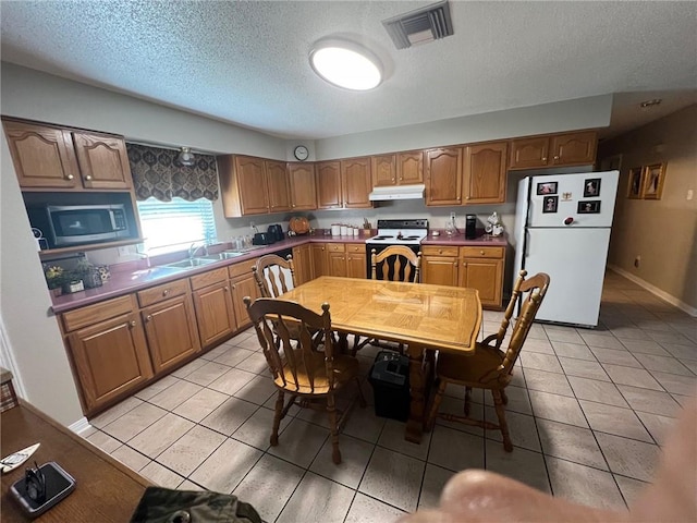 kitchen featuring light tile patterned flooring, a textured ceiling, white appliances, and sink