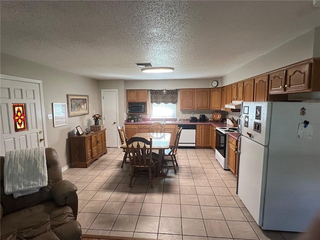 kitchen with sink, white appliances, a textured ceiling, and light tile patterned floors