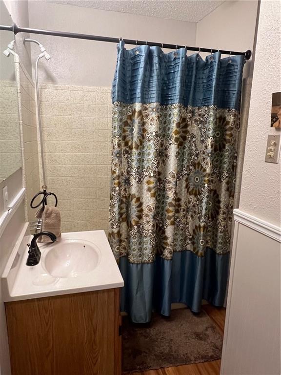 bathroom with vanity, wood-type flooring, a textured ceiling, and curtained shower