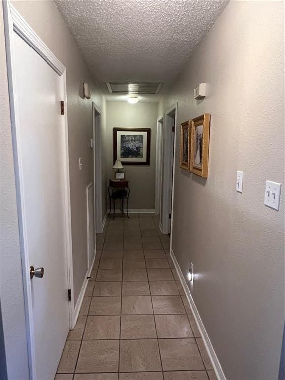 hall featuring light tile patterned floors and a textured ceiling