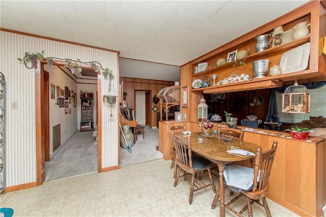 dining room with wood walls and ornamental molding