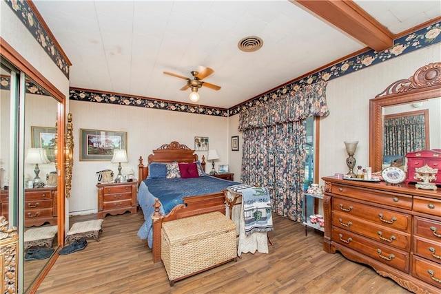 bedroom with beam ceiling, a closet, ceiling fan, and hardwood / wood-style floors