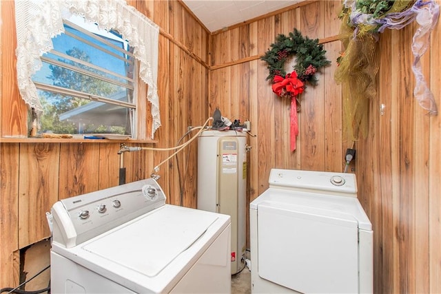 washroom featuring electric water heater, wood walls, and independent washer and dryer