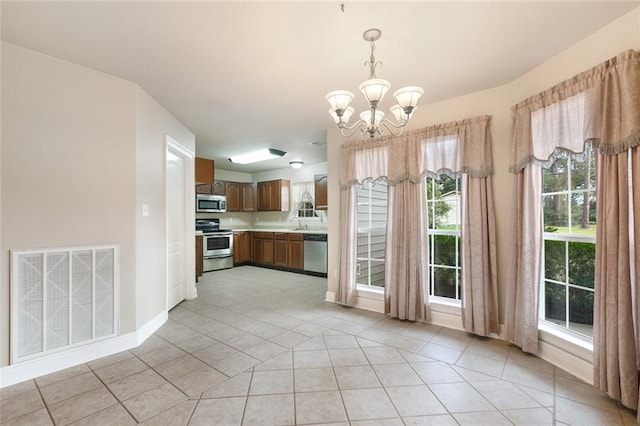 kitchen with sink, an inviting chandelier, pendant lighting, light tile patterned floors, and appliances with stainless steel finishes