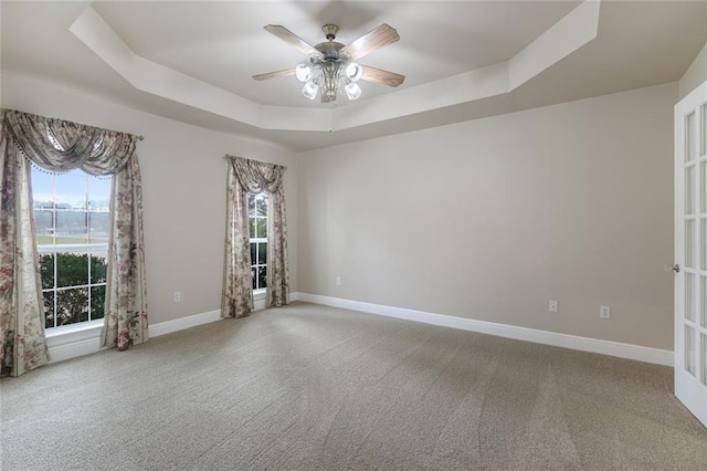 carpeted empty room featuring ceiling fan, a raised ceiling, and french doors