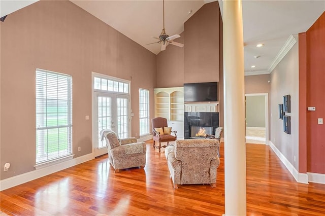 living room featuring high vaulted ceiling, light hardwood / wood-style flooring, ceiling fan, and a healthy amount of sunlight