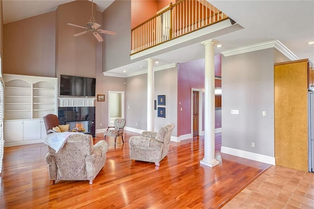 living room featuring ornate columns, light hardwood / wood-style flooring, and a towering ceiling