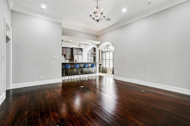 unfurnished living room with hardwood / wood-style floors, a notable chandelier, and ornamental molding